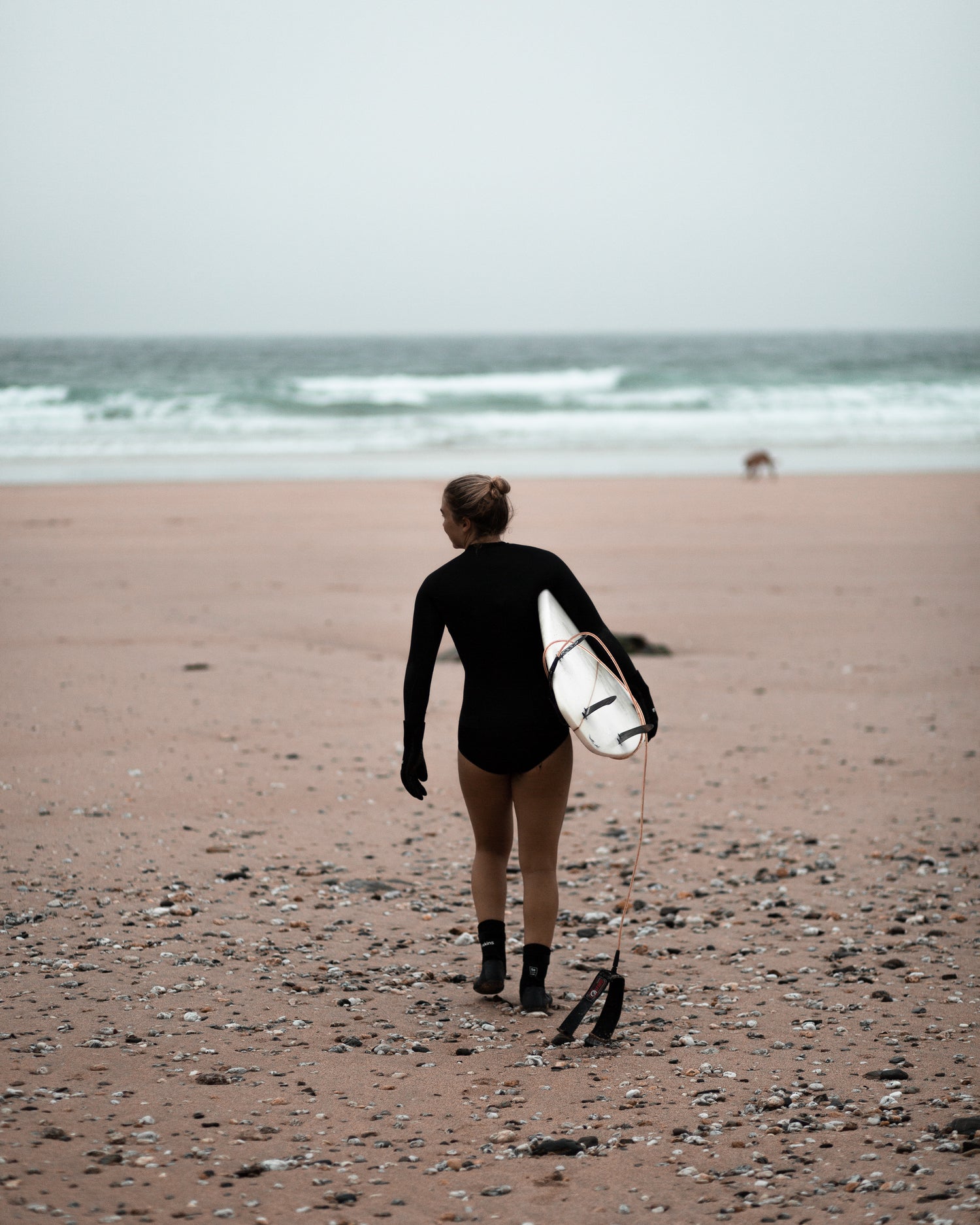 Surfer walking on the beach after getting some waves surfboard mounts from www.noir.design